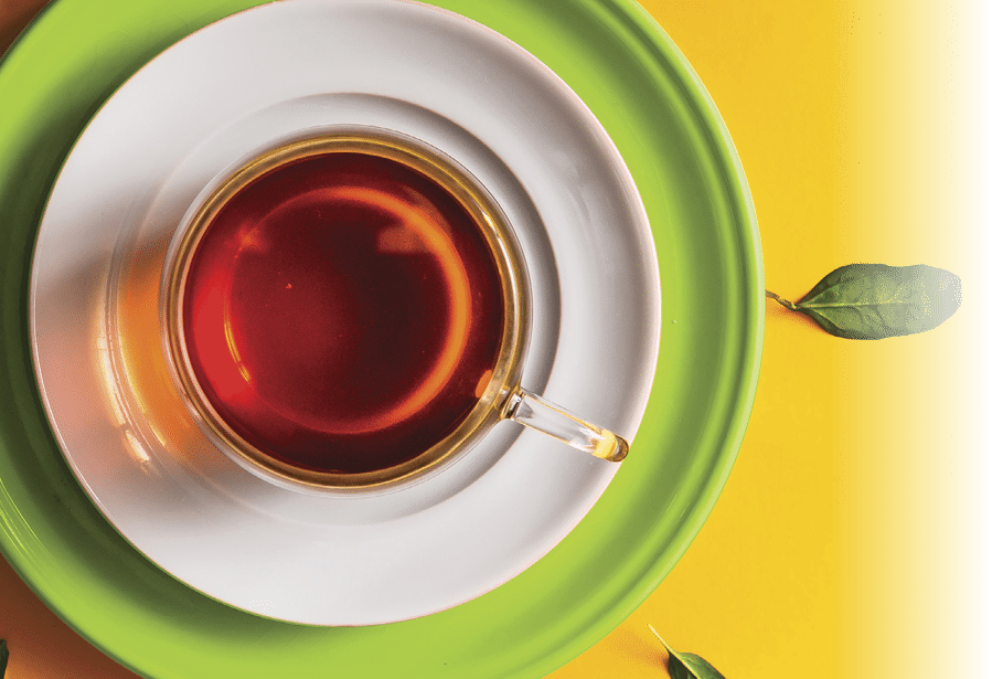 Tea in glass cup with green leaves on orange background. Time concept.