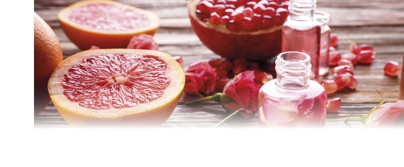 Perfume bottles, roses and fresh fruits on wooden table