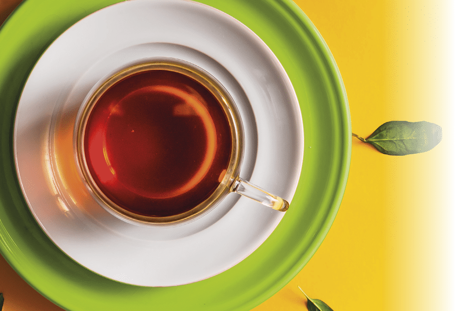 Tea in glass cup with green leaves  on orange background  Time concept 