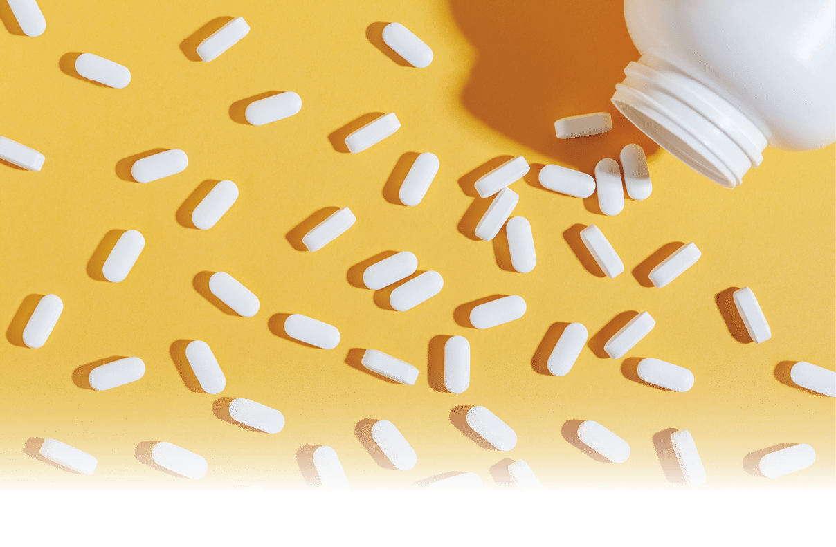 White pills are poured from a jar on a yellow background  Food supplement, multivitamins, medications