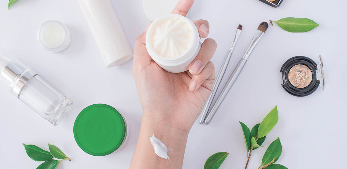 Woman giving the skin care cream container and apply on her hand with flat lay background
