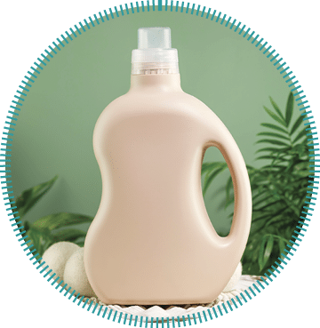 Natural laundry detergent mockup. Washing detergent concept with bottles of washing gel or fabric softener on a white laundry basket on a green background with green leaves. Laundry day