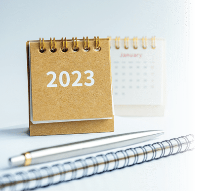 Happy new year 2023 banner background. 2023 numbers year on small beige desk calendar cover on notepad with pen on white background with copy space, to do list concept.