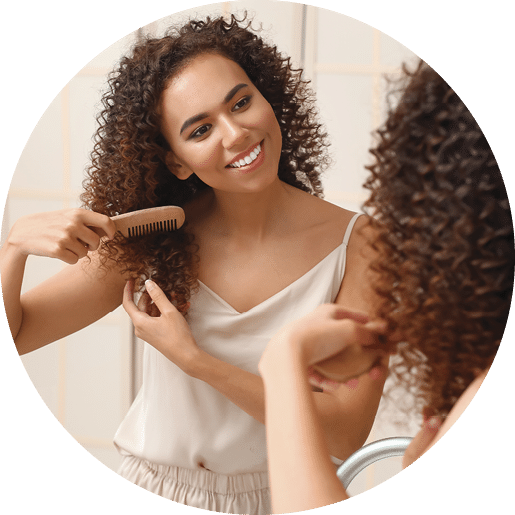 Young African-American woman combing her hair near mirror in bathroom