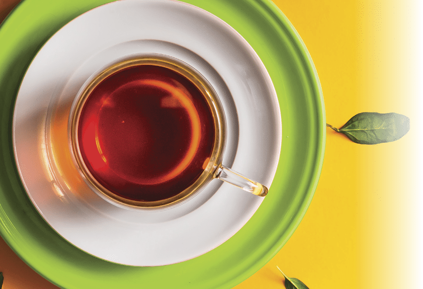 Tea in glass cup with green leaves on orange background. Time concept.