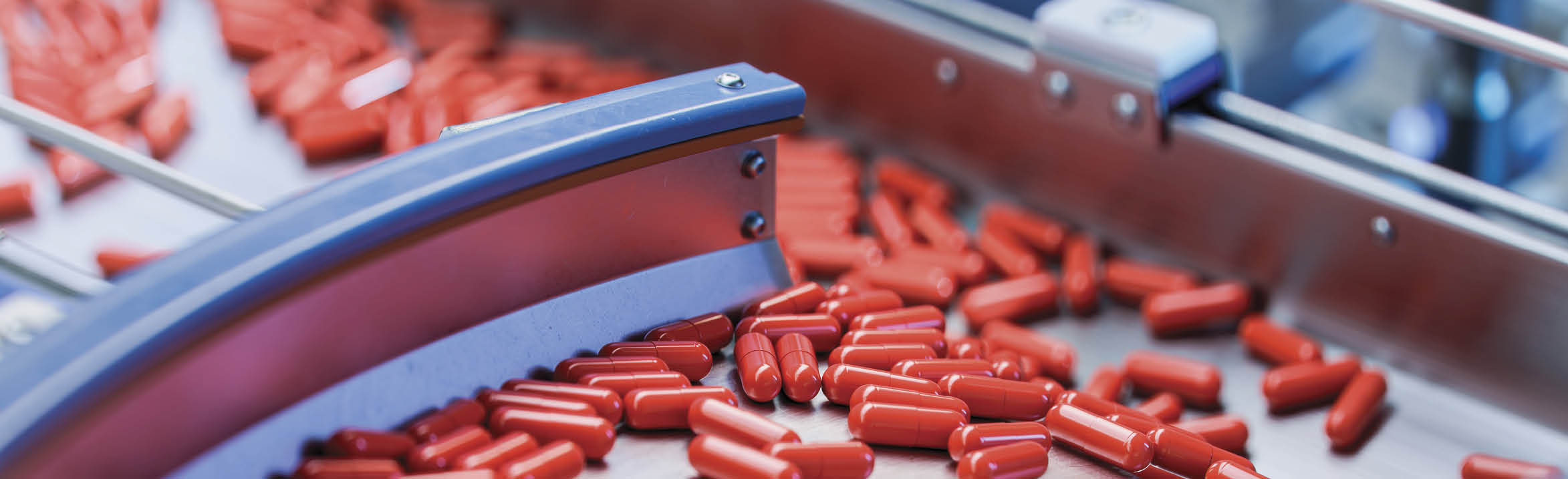Red Capsules on Conveyor at Modern Pharmaceutical Factory. Medical Drug Production Line. Tablet and Capsule Manufacturing Process.