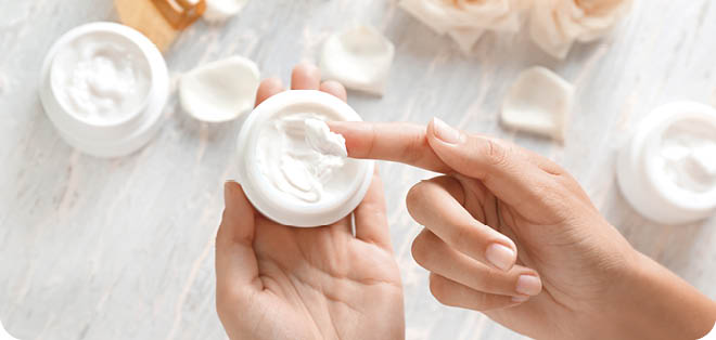 Young woman applying body cream, closeup