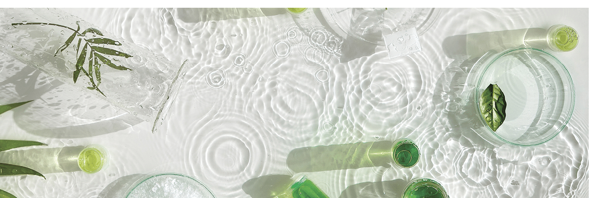 Cosmetic skincare background. Herbal medicine with green leaves. Natural sunlight, long shadows. Splashes of water, splashes. Chemical glassware, petri dishes, vials. Natural skincare background.