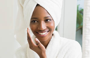 Young woman applying moisturizer to her skin in the bathroom