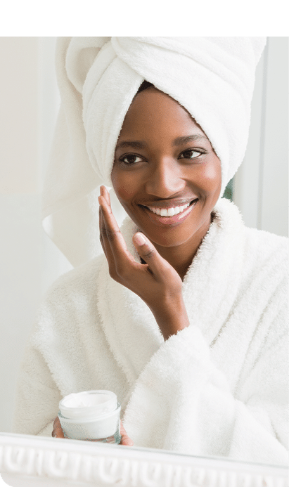 Young woman applying moisturizer to her skin in the bathroom