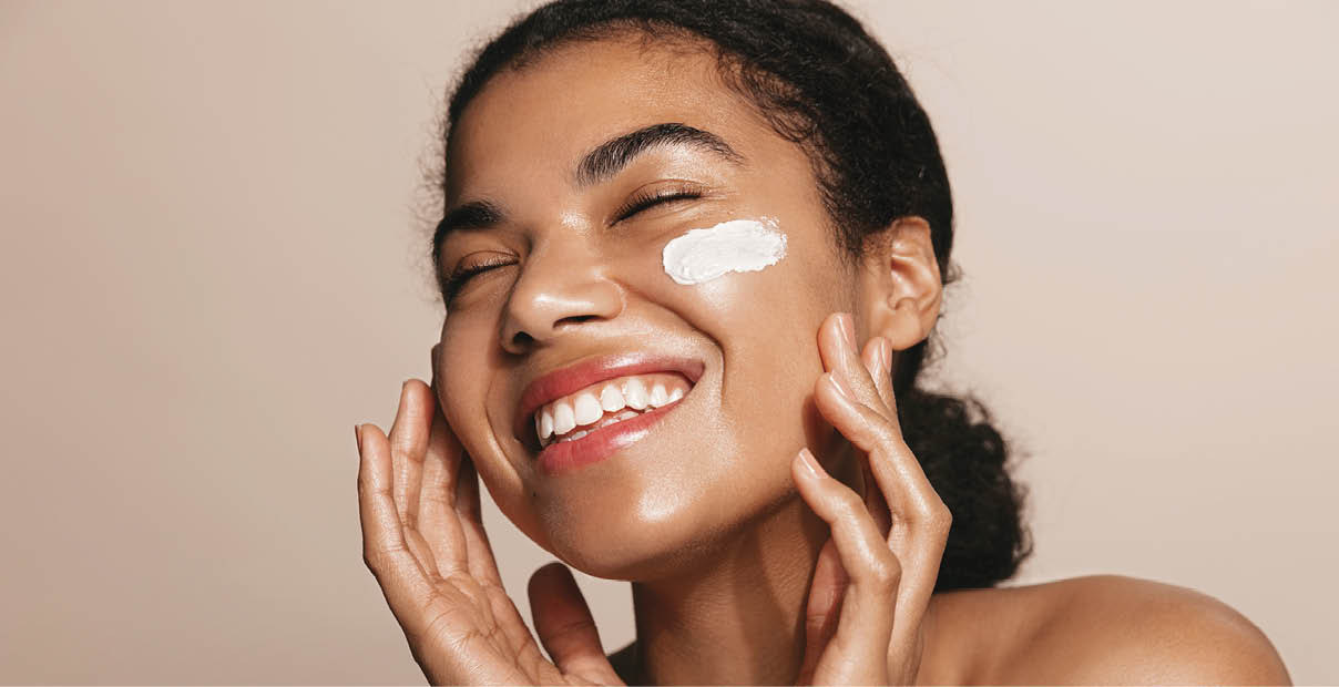 Smiling woman using skincare product. Female taking face cream to apply on facial skin