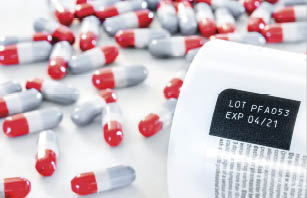 Expired date and lot number label printed on medicine bottle with blurred background of pile of painkiller pills awareness expiration information on packaging from the manufacturer. Medication.
