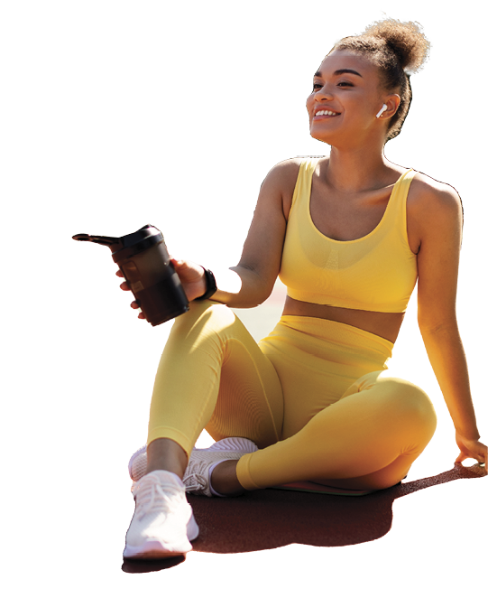 Energy, Vitality, Wellness Concept. Smiling African American woman sitting on basketball field ground, holding shaker, drinking water, taking break after outdoors exercise, wearing wireless earbuds
