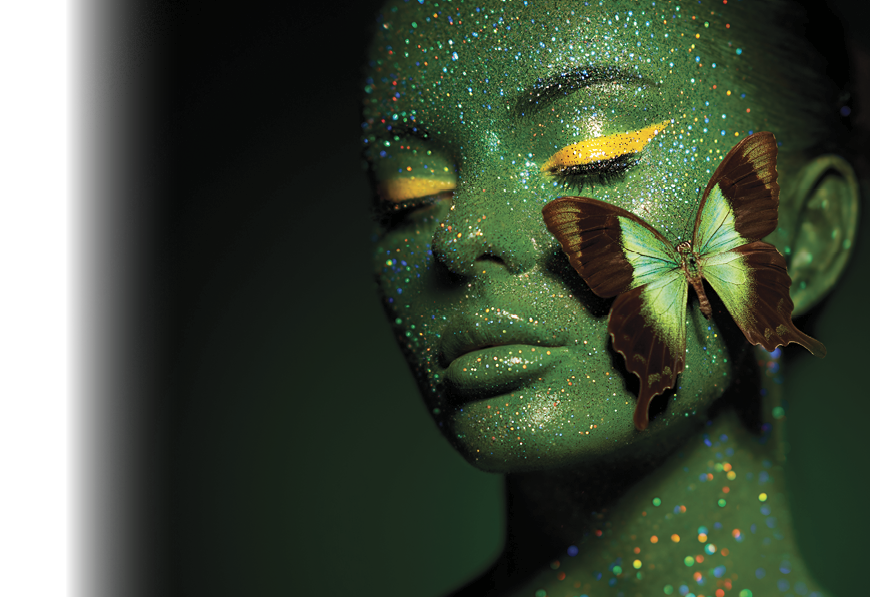Fashion model woman skin face in bright sparkles with green butterfly colorful neon lights, beautiful girl sexy lips. Glowing art green skin make-up. Glitter metallic shine silver green makeup